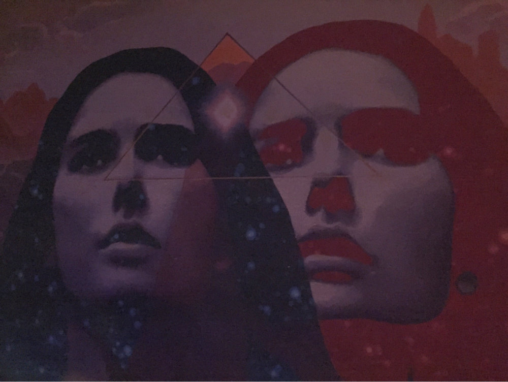 a mural of 2 faces in an arcade