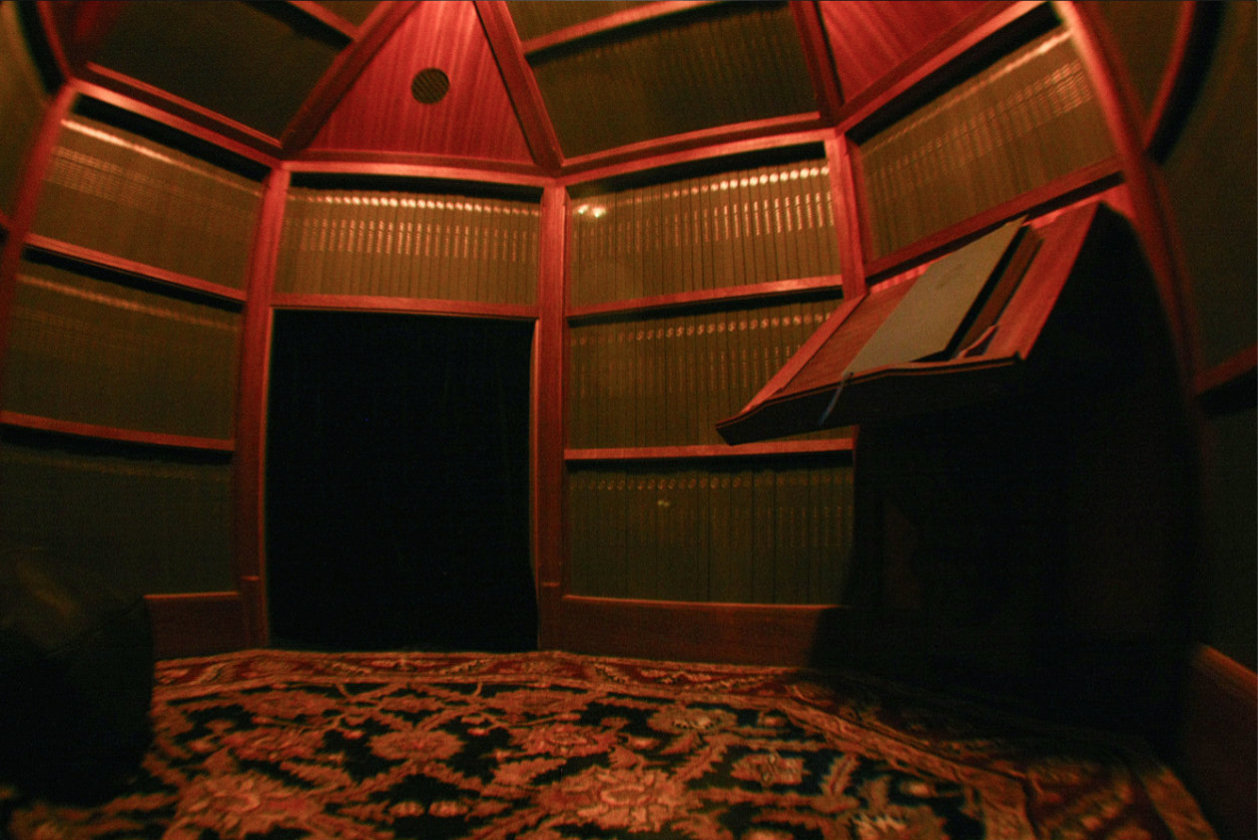 a hexagonal library stacked with book and a sole lectern